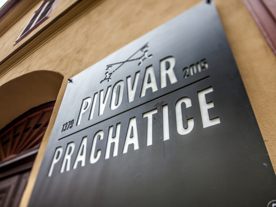 Metal plaque on a beige wall reading PIVOVAR PRAHCHATICE 2015, with a decorative emblem above, mounted beside a window arch.