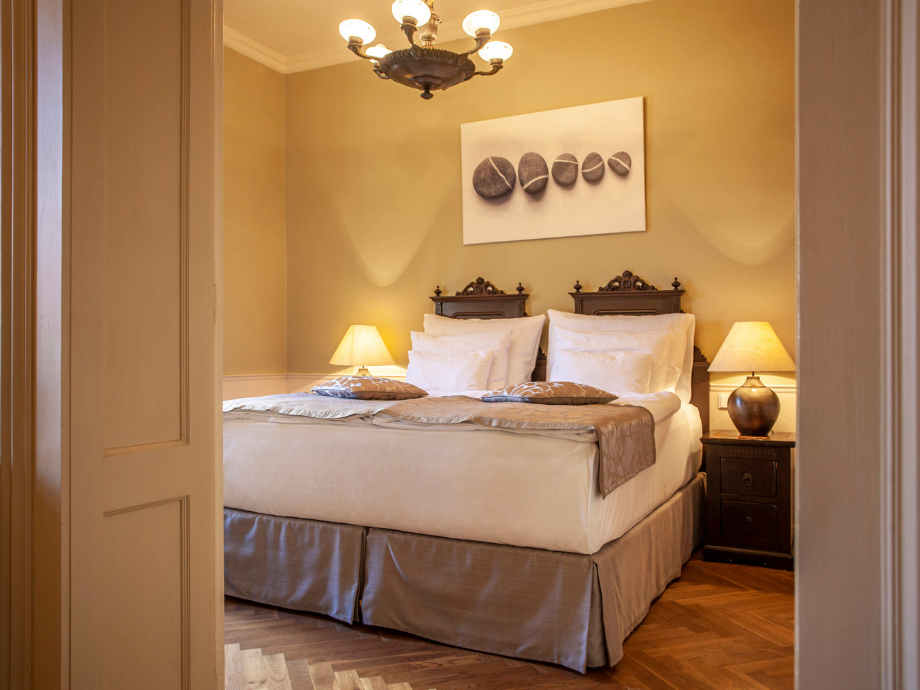 Elegant hotel bedroom with a large bed, two nightstands, and warm lamps on either side.
