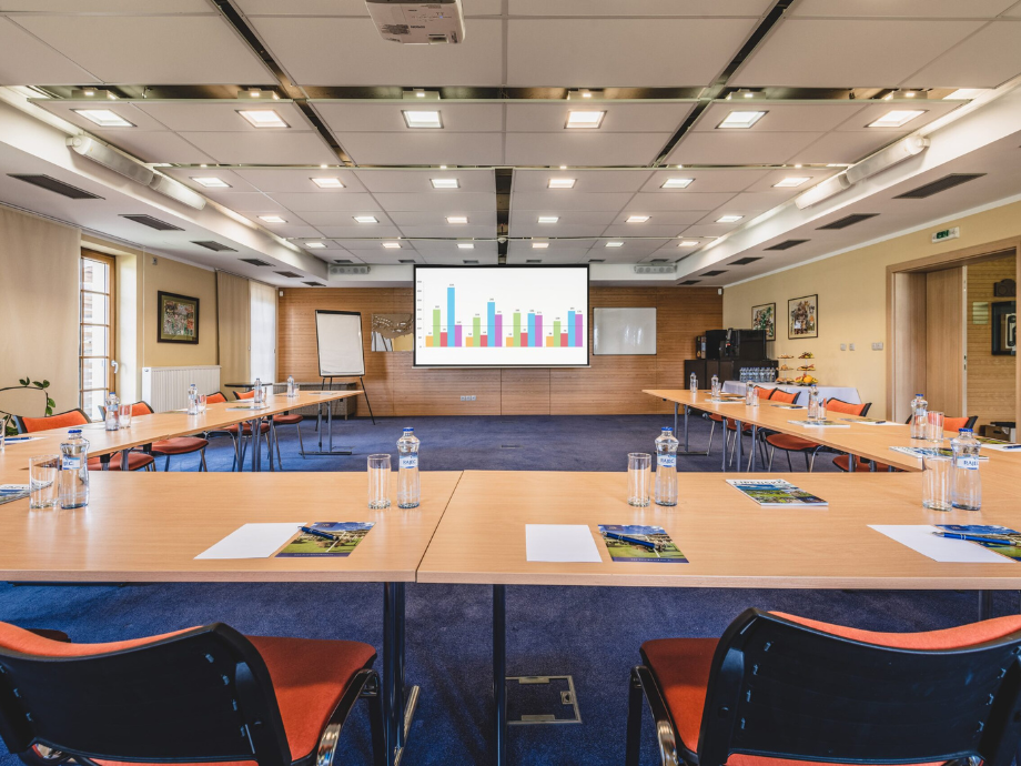 Conference room set up for a presentation with a large screen displaying a bar chart at the front of the room