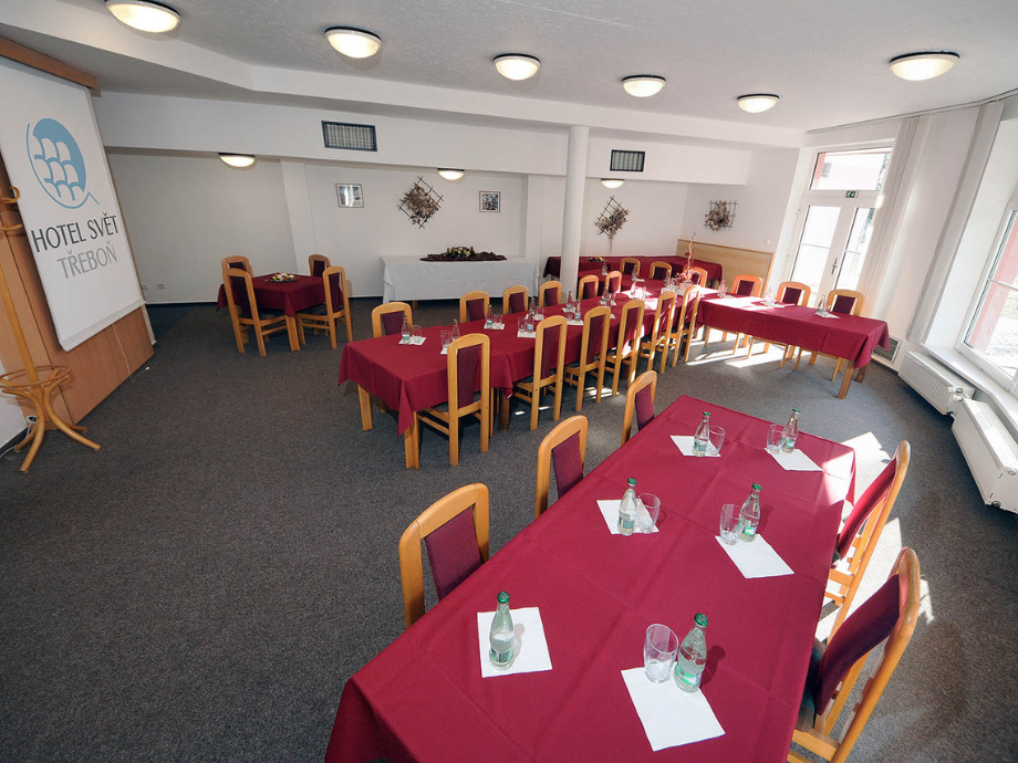 Banquet room set with red tablecloths, bottles of water and glasses at each place, arranged for a meeting or event.