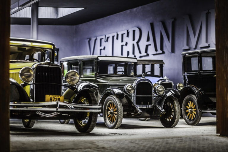 Row of vintage early-20th-century cars parked indoors in a museum, with a large 'VETERAN' mural on the wall behind them] , but need to be careful.